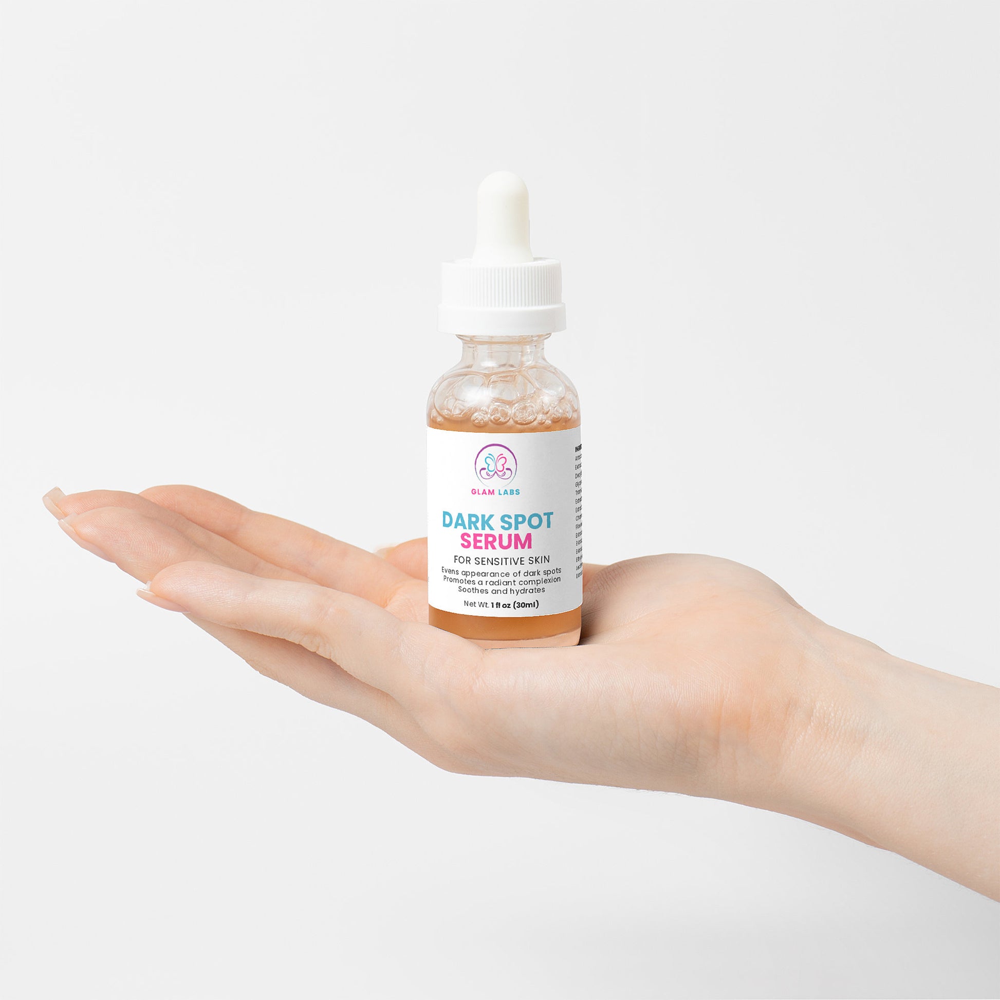 Glam Labs Dark Spot Serum for Sensitive Skin in glass dropper bottle held in palm on white background